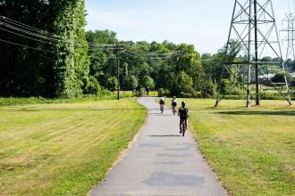Three cyclists ride their bikes down Salem Creek Parkway near downtown Winston-Salem.