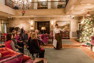 Guide speaking to seated group inside Reynolda House decorated for holidays.