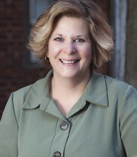 Headshot of blond woman in a green blazer