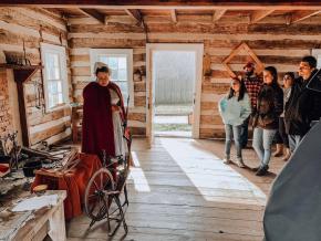 A costumed interpreter at Historic Bethabara Park showcases traditional Moravian hobbies and crafts to a group tour.