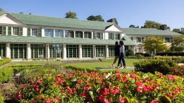 A man and woman tour the Reynolda grounds in front of the Reynolda House Museum of American Art.